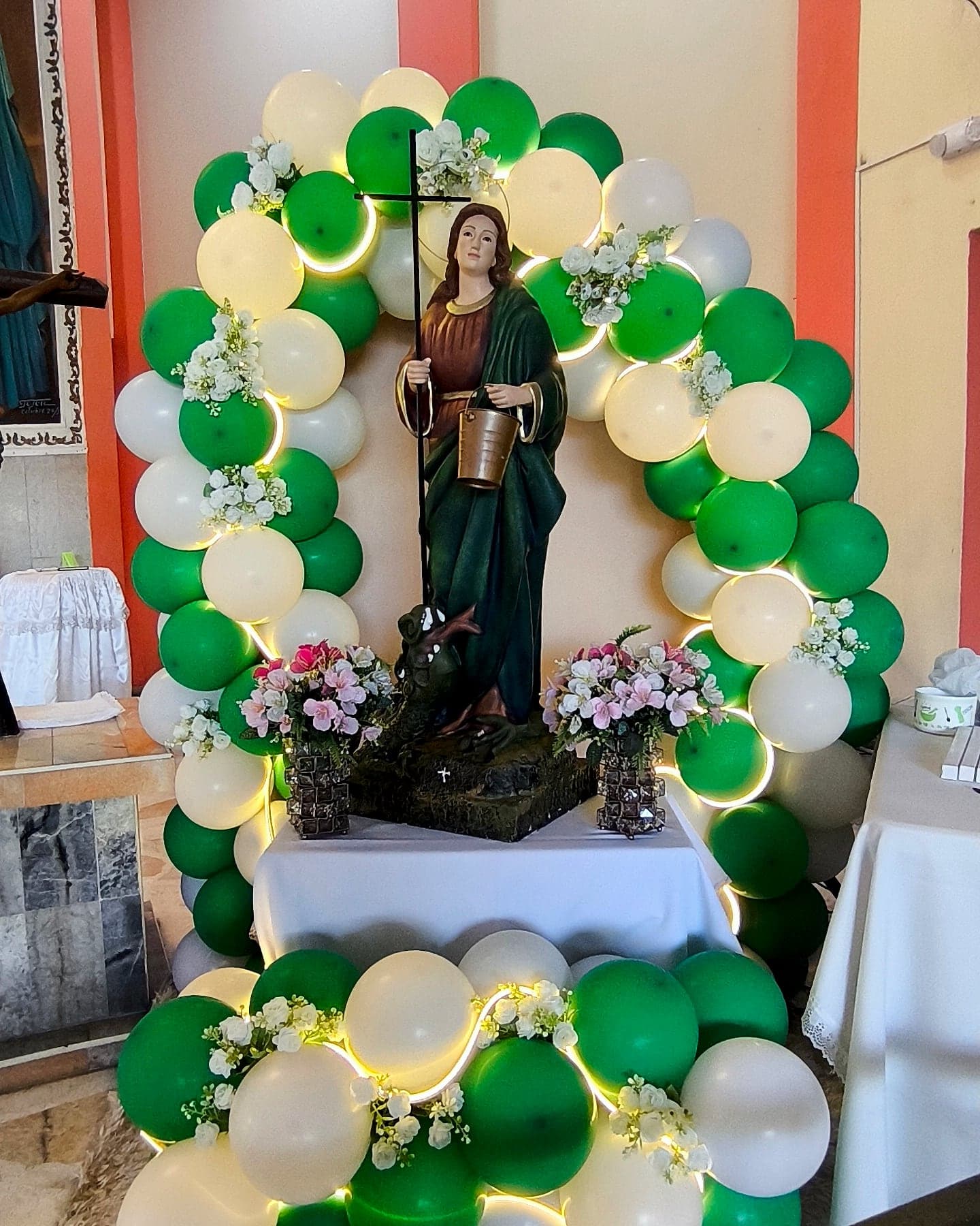Arco de globos verde y blanco con flores para celebración religiosa