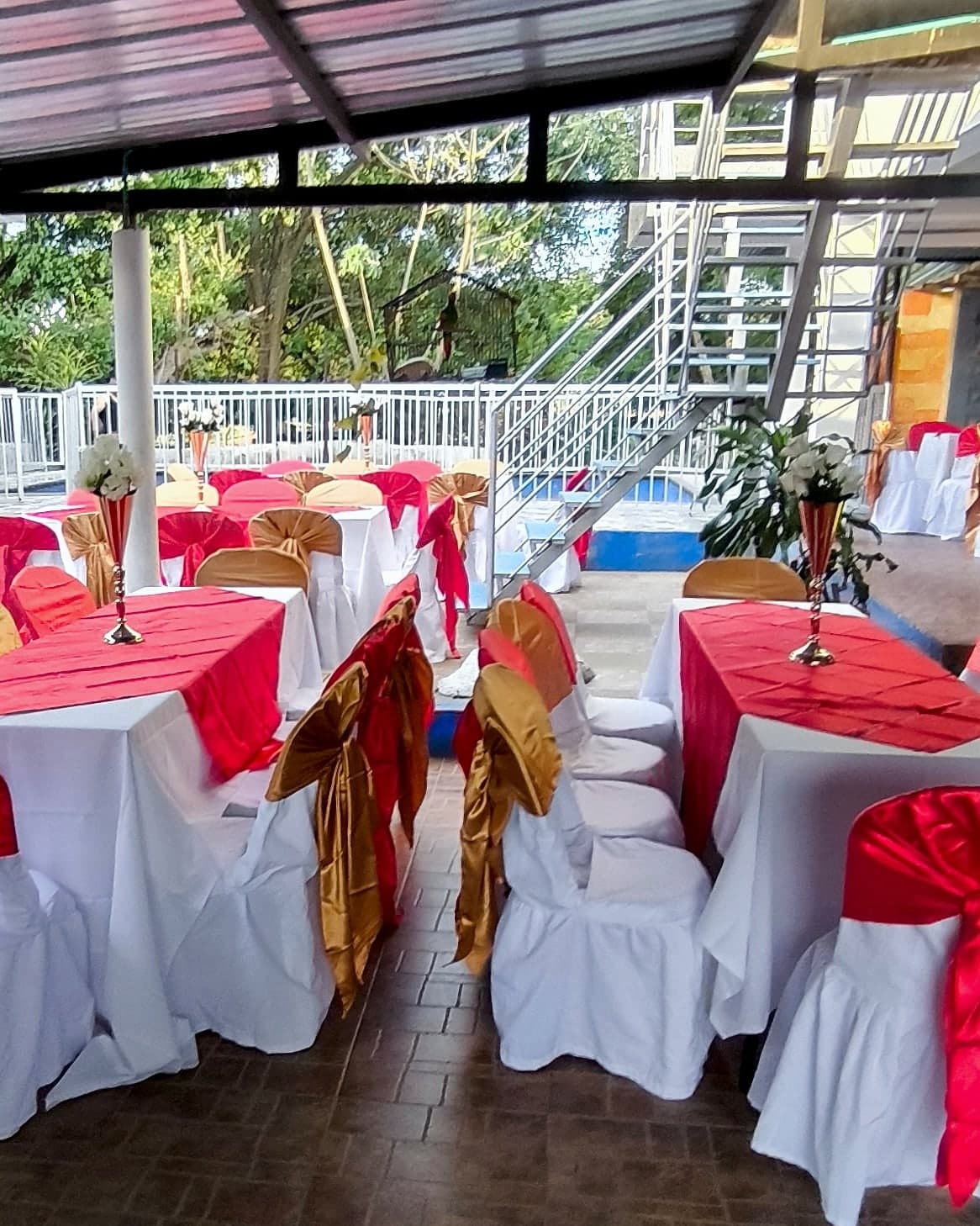Mesas vestidas en blanco y rojo con sillas de moño rojo y dorado